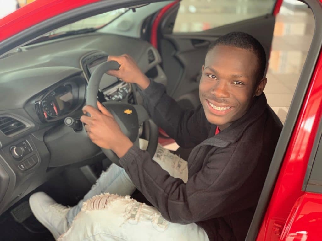 boy sitting in drivers seat of red car