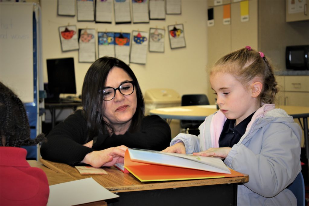 teacher assisting student at desk