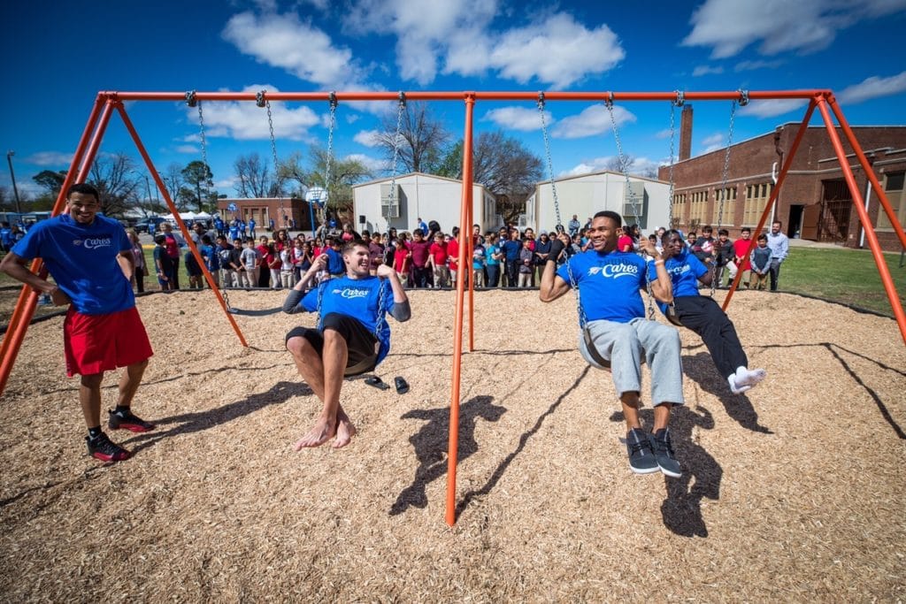 OKC Thunder players swinging at playground