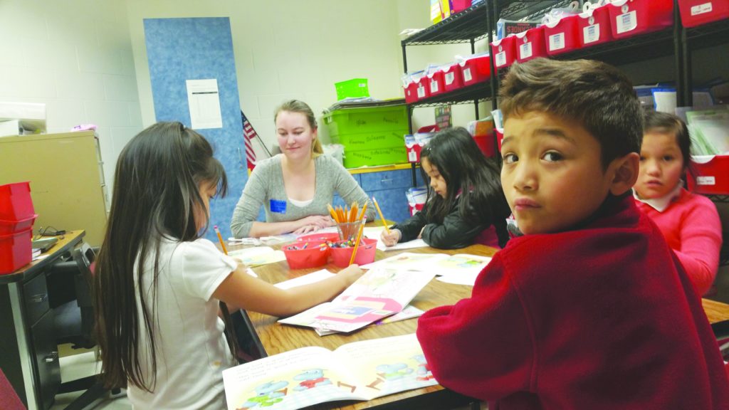 kids and teacher at desk working